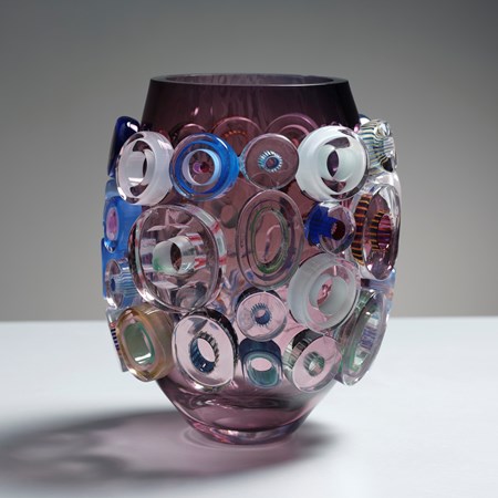 transparent aubergine and purple short barrel shaped vase with surface decoration of raised chubby flat rings in pink celadon blue and pink hand made from glass